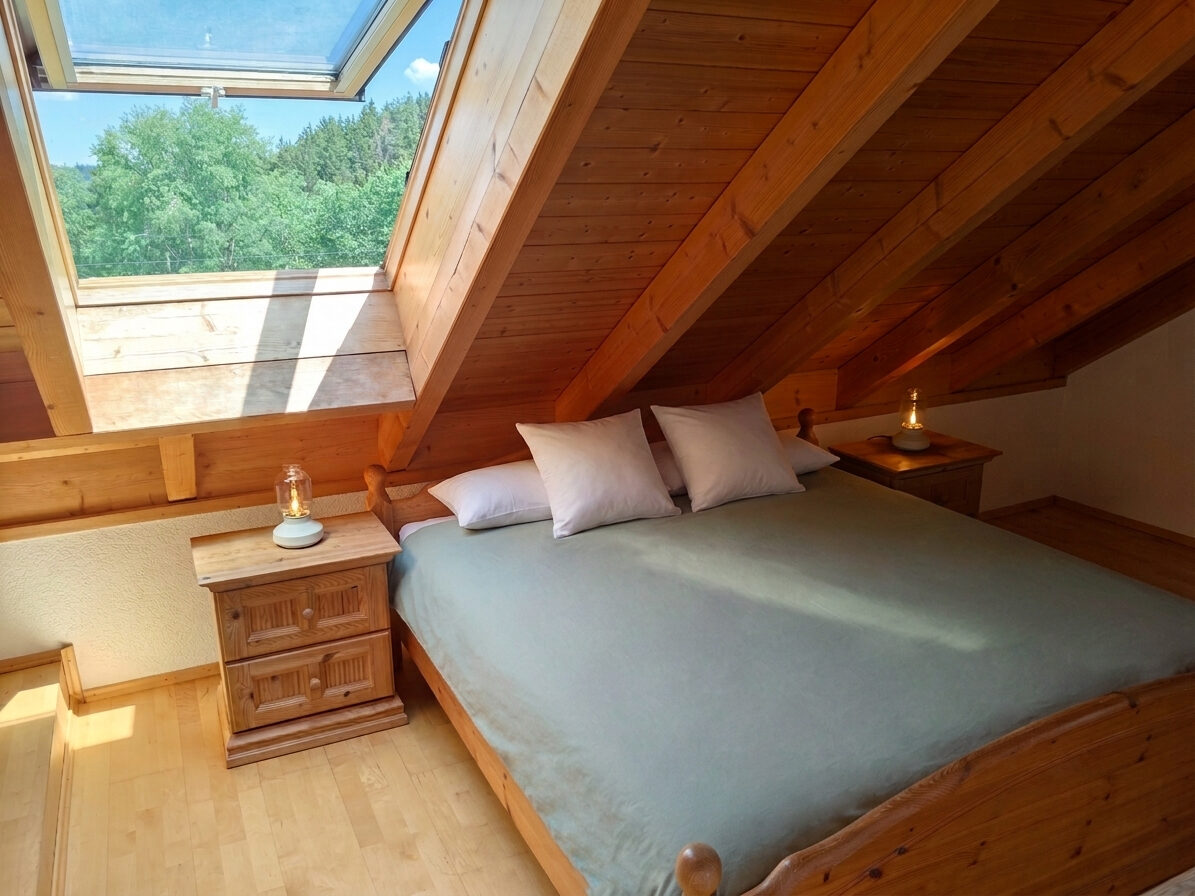 Schlafzimmer mit Doppelbett unter dem Dachgebälk