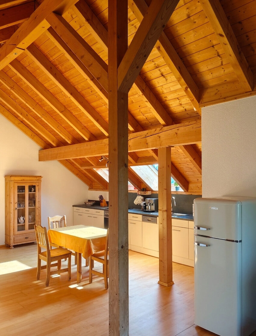 Offener Wohn- und Küchenbereich mit Esstisch unter dem historischen Dachgebälk im Chalet-Loft Wutachblick